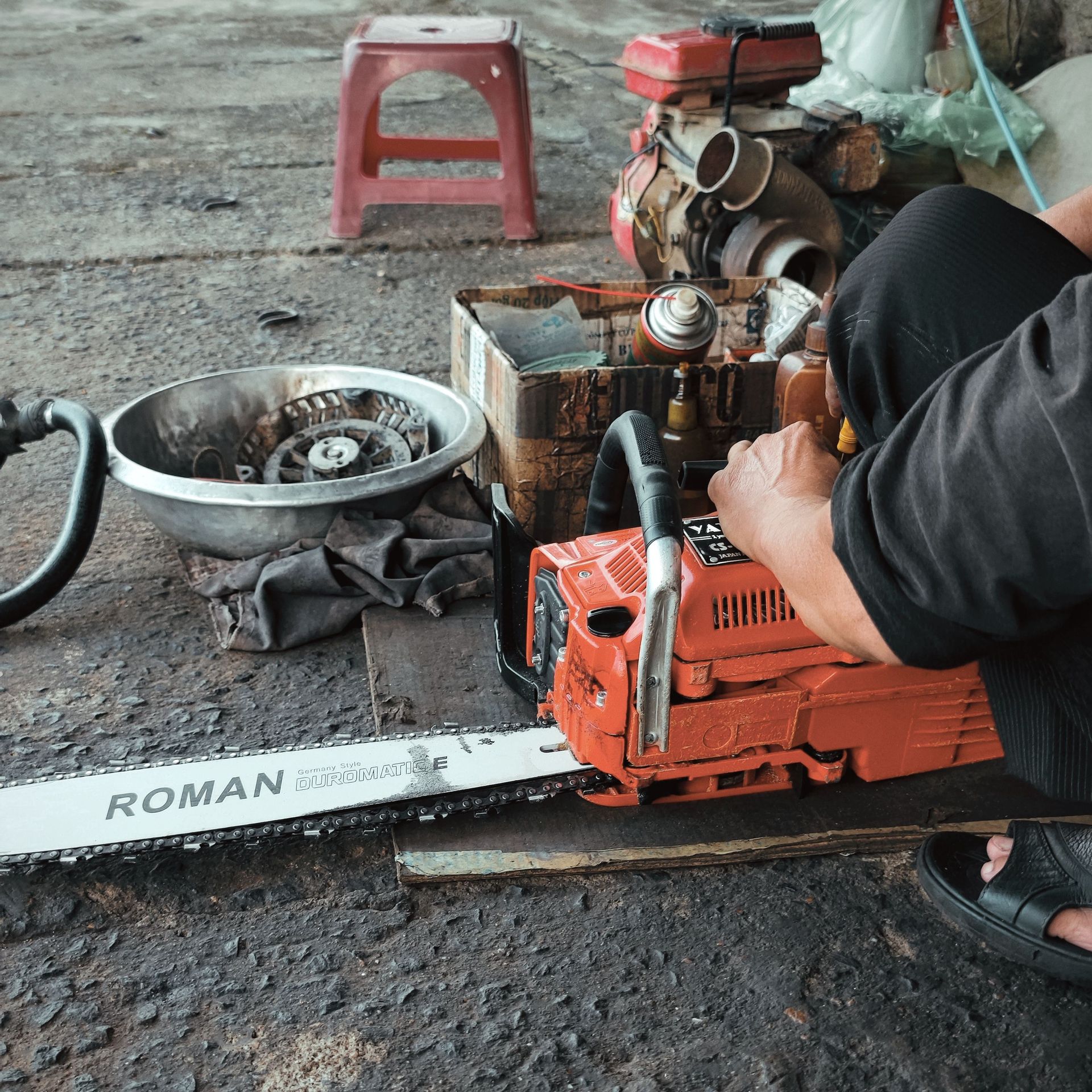 A focused scene in a mechanic's workshop with a chainsaw being repaired in Phú Yên, Vietnam.